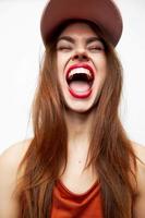 femme dans une casquette ouvre le sien bouche large avec amusement émotions fermé yeux Orange robe photo