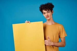 émotif homme avec frisé cheveux Jaune affiche dans le mains de copie espace photo