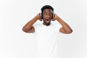 homme de africain apparence dans écouteurs dans une blanc T-shirt écoute à la musique divertissement photo