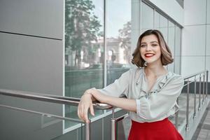 jolie femme rouge jupe café tasse près bâtiment en plein air posant photo