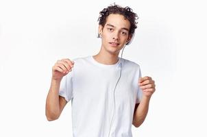blanc écouteurs pour écoute à la musique et content gars dans une T-shirt sur une lumière Contexte tondu vue photo