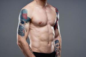 homme avec tatouages sur le sien bras nu torse pompage en haut abdos faire des exercices photo