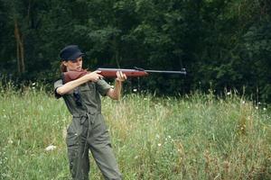 femme soldat dans une vert salopette avec une pistolet prend objectif armes photo
