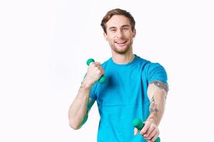 homme dans bleu T-shirt en portant haltères aptitude exercice photo