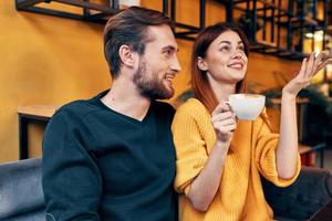 une femme dans l'amour avec une tasse de café et une content homme à une table dans une café intérieur copains la communication photo