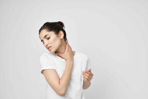 femme dans une blanc T-shirt douleur dans le cou lumière Contexte photo