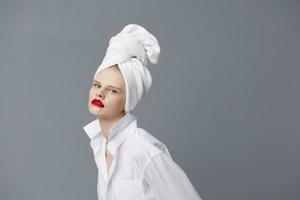 glamour femme avec une serviette sur le sien tête dans une blanc chemise isolé Contexte photo