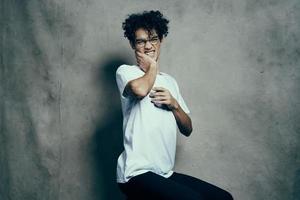 mignonne gars dans blanc T-shirt et frisé cheveux mode studio mode de vie photo