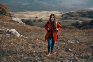 Voyage tourisme Jeune femme dans rouge veste et jeans avec sac à dos dans le montagnes dans l'automne photo