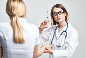 une femme détient une seringue dans sa main et une femelle patient dans une blanc T-shirt est effrayé modèle photo