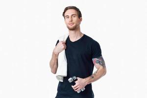 des sports homme dans une noir T-shirt avec haltères dans le sien mains aptitude des exercices photo