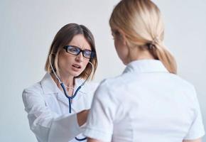 professionnel femme médecin dans médical robe et des lunettes bleu stéthoscope patient photo