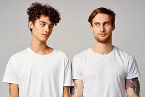 deux Hommes dans blanc t-shirts sont permanent suivant à relation amicale émotions photo