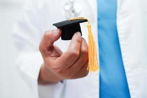 femme médecin asiatique tenant un chapeau de graduation à l'hôpital, concept d'éducation médicale. photo