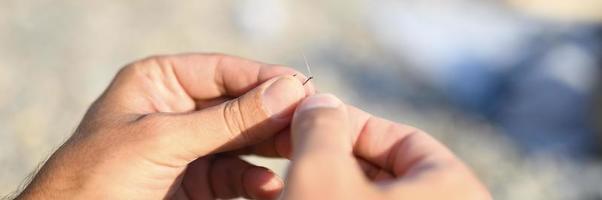 Les mains de l'homme attachant une ligne de pêche sur un hameçon photo