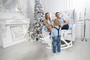 famille à Noël. mère père et enfant jouer contre le Contexte de une Noël arbre. Parents et fils dans le Nouveau an. photo