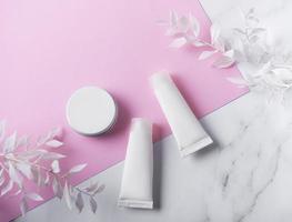 tubes blancs de crème sur fond de marbre et rose photo