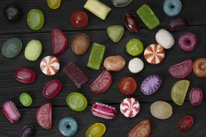 des sucreries sur une foncé Contexte. multicolore caramel sur une en bois planche. bonbons. photo