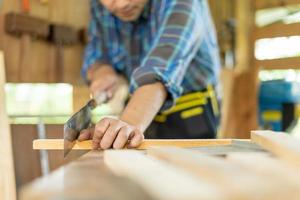 asiatique homme propriétaire une petit meubles affaires est en train de préparer bois pour production. Charpentier Masculin est régler bois à le voulu taille. architecte, designer, intégré, professionnel bois, artisan, atelier. photo