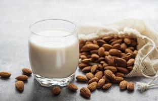 bouteille en verre avec du lait d'amande et des amandes sur la table photo