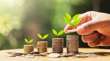 main en mettant pièces de monnaie sur empiler avec plante croissance sur argent . concept la finance et comptabilité photo