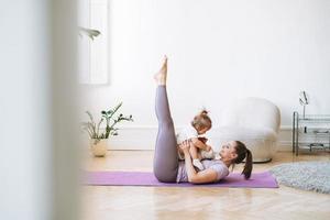 jeune femme fit maman avec bébé fille faisant du fitness sur tapis à la maison photo