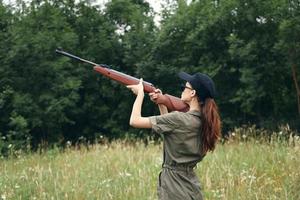 femme sur la nature avec une fusil Frais air Voyage chasse vert salopette photo