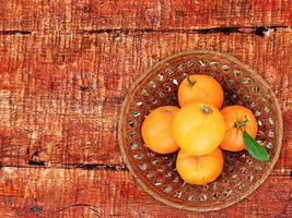 Oranges dans un bol en osier sur un fond de table en bois