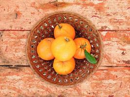 Oranges dans un bol en osier sur un fond de table en bois