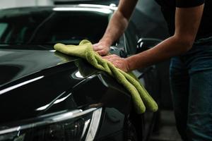 l'homme nettoie la carrosserie avec une serviette photo