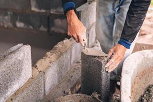 main de ouvrier plâtrage ciment sur brique mur à construction site photo