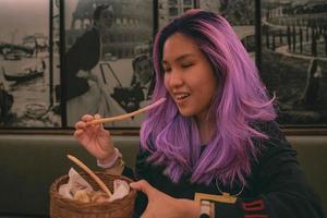 violet cheveux asiatique femme en mangeant une gressin à le italien restaurant photo