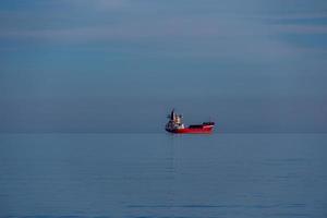 rouge cargaison navire dans le bleu mer calme minimaliste paysage photo