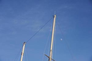 mâts de yacht contre un ciel bleu avec la lune