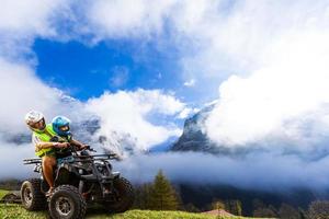 content famille équitation et à la recherche quad bicyclette sur Montagne. mignonne garçon sur quadricycle. famille été vacances activité. photo