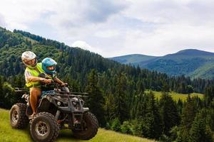 content famille équitation et à la recherche quad bicyclette sur Montagne. mignonne garçon sur quadricycle. famille été vacances activité. photo