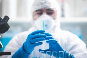 scientifique tenant une seringue avec un liquide bleu dedans photo