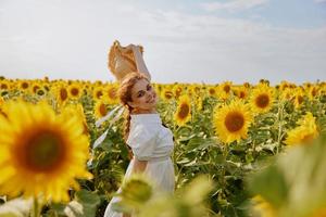 souriant femme dans tournesol champ chapeau dans mains la nature paysage photo