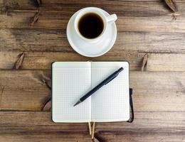 café dans une tasse et une bloc-notes avec une stylo, Haut voir. photo