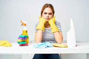 femme séance à le table caoutchouc gants nettoyage travaux ménagers détergent un service photo