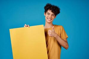 de bonne humeur gars avec frisé cheveux Jaune affiche maquette La publicité bleu Contexte photo