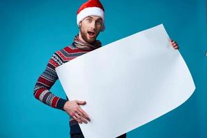 de bonne humeur homme dans une Père Noël chapeau en portant une bannière vacances bleu Contexte photo