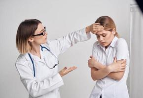 médecin femme les mesures le Température de le patient et une stéthoscope sur le cou photo
