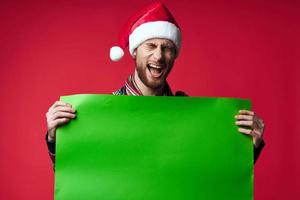 Beau homme dans une Père Noël chapeau en portant une bannière vacances studio posant photo