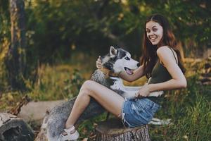 femme et sa rauque chien Heureusement en jouant en plein air dans le parc parmi le des arbres sourire avec les dents dans le l'automne marcher avec sa animal de compagnie photo