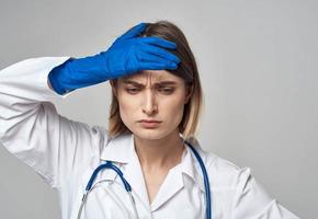 une infirmière dans une médical robe et bleu gants gestes avec une stéthoscope autour sa cou photo