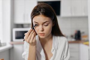 magnifique femme avec eye-liner crayon maquillage cosmétologie pièce cuisine photo