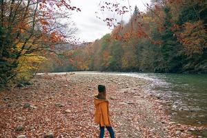 femme dans une Jaune veste près le rivière montagnes la nature marcher photo