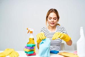 une nettoyage Dame est assis à une table fournir Entretien ménager prestations de service lumière Contexte photo