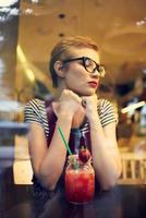 femme avec court coiffure dans une café cocktail du repos pensif Regardez photo